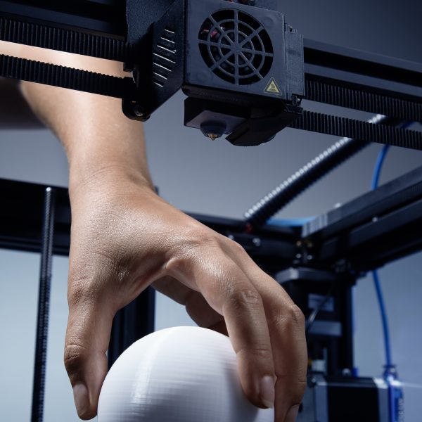 A gender-neutral hand lifting up from the structure 3d printed round object made from recycled plastic. Futuristic concept of new working possibilities for small businesses by 3D printing. Jpg photo